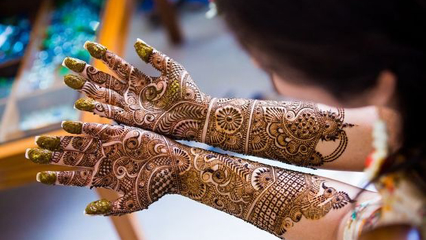 Professional artist applying hand Mehandi designs with organic henna